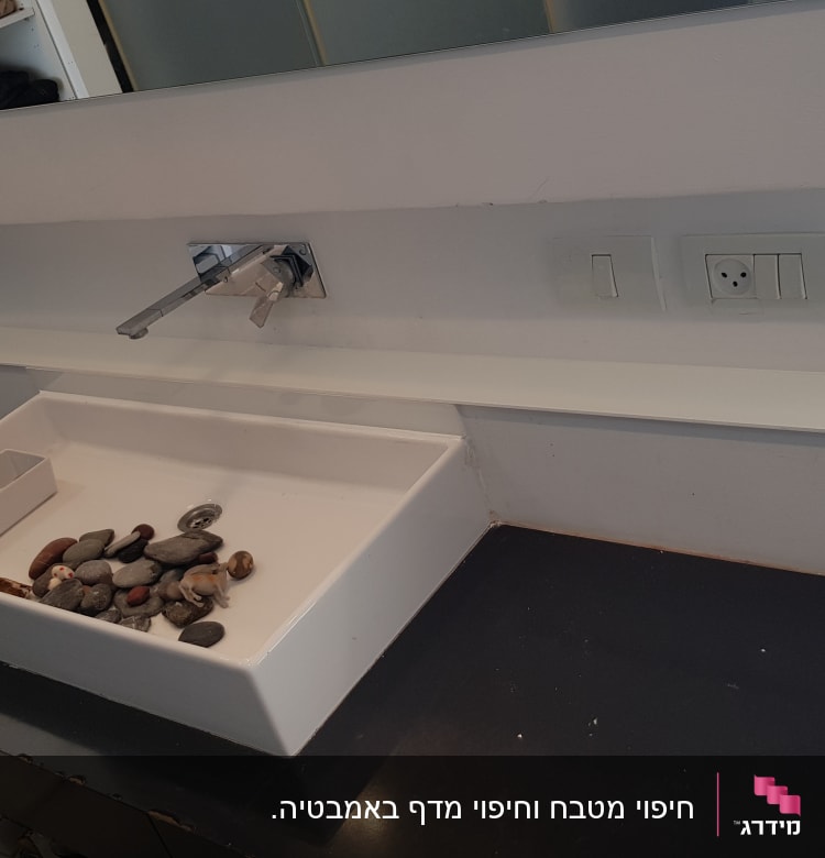 ברז זכוכית מעל כיור לבן עם אבנים